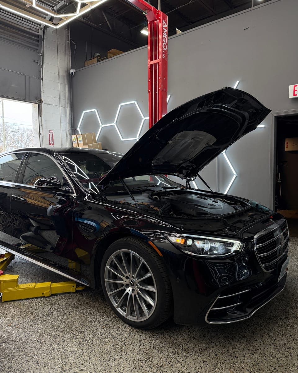 Black Mercedes-Benz sedan with its hood raised inside the Pro Tech Auto bay in Manchester, NH.