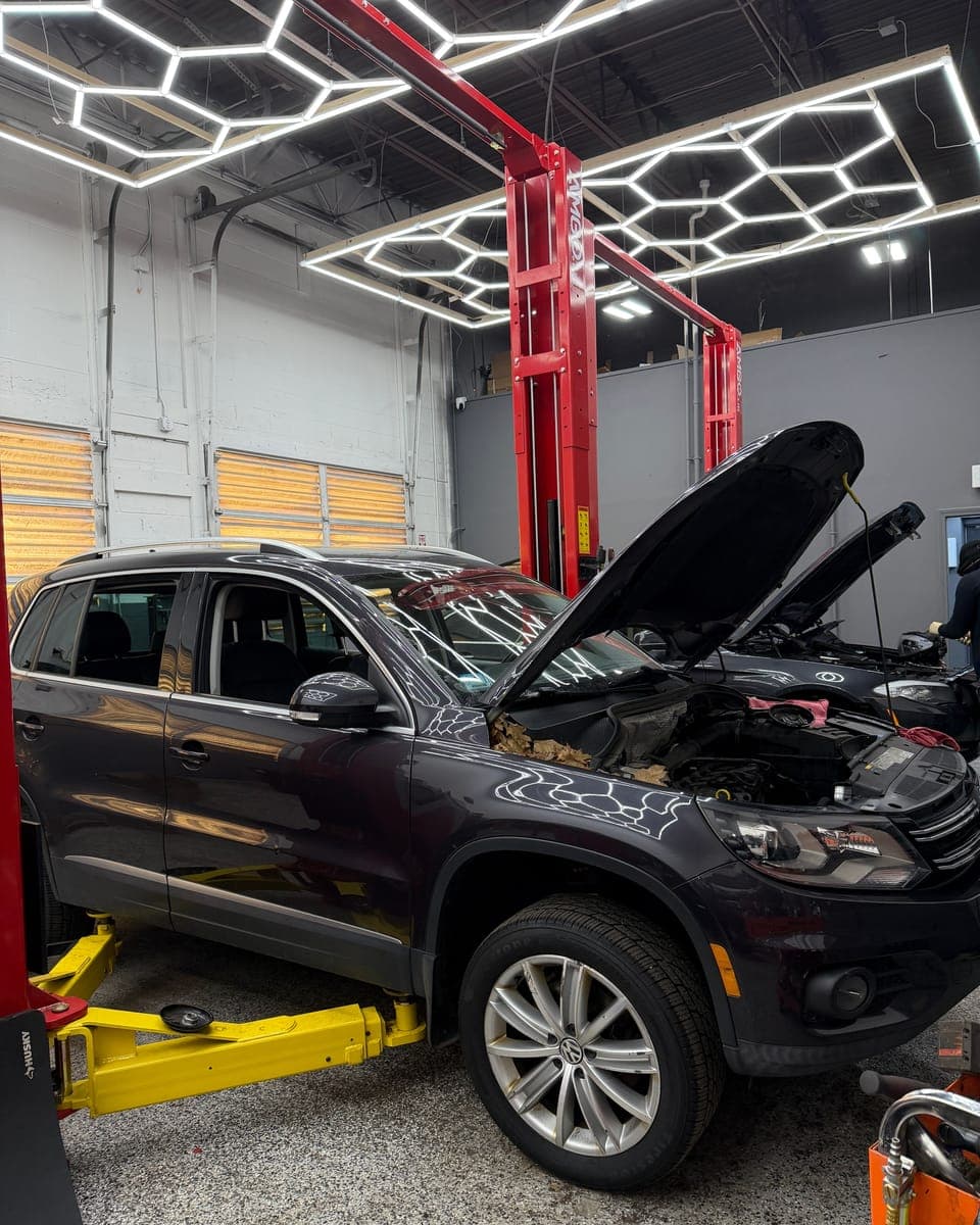 Volkswagen Tiguan on a lift with its hood open at Pro Tech Auto in Manchester, NH.