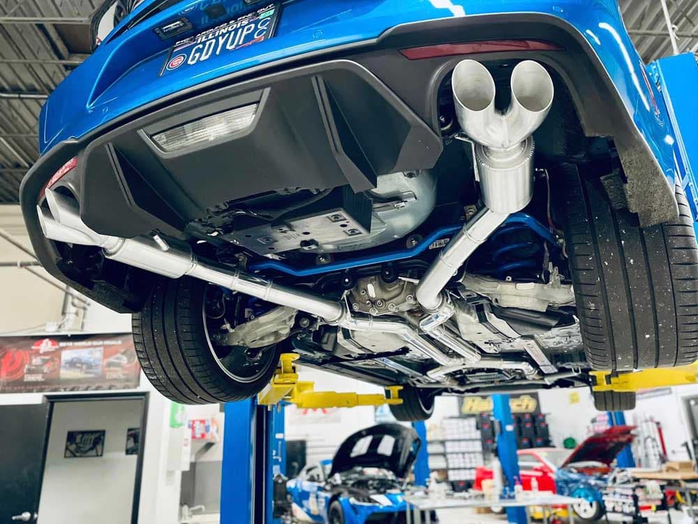 Underside view of a vehicle exhaust system during a muffler and hanger repair at Pro Tech Auto.