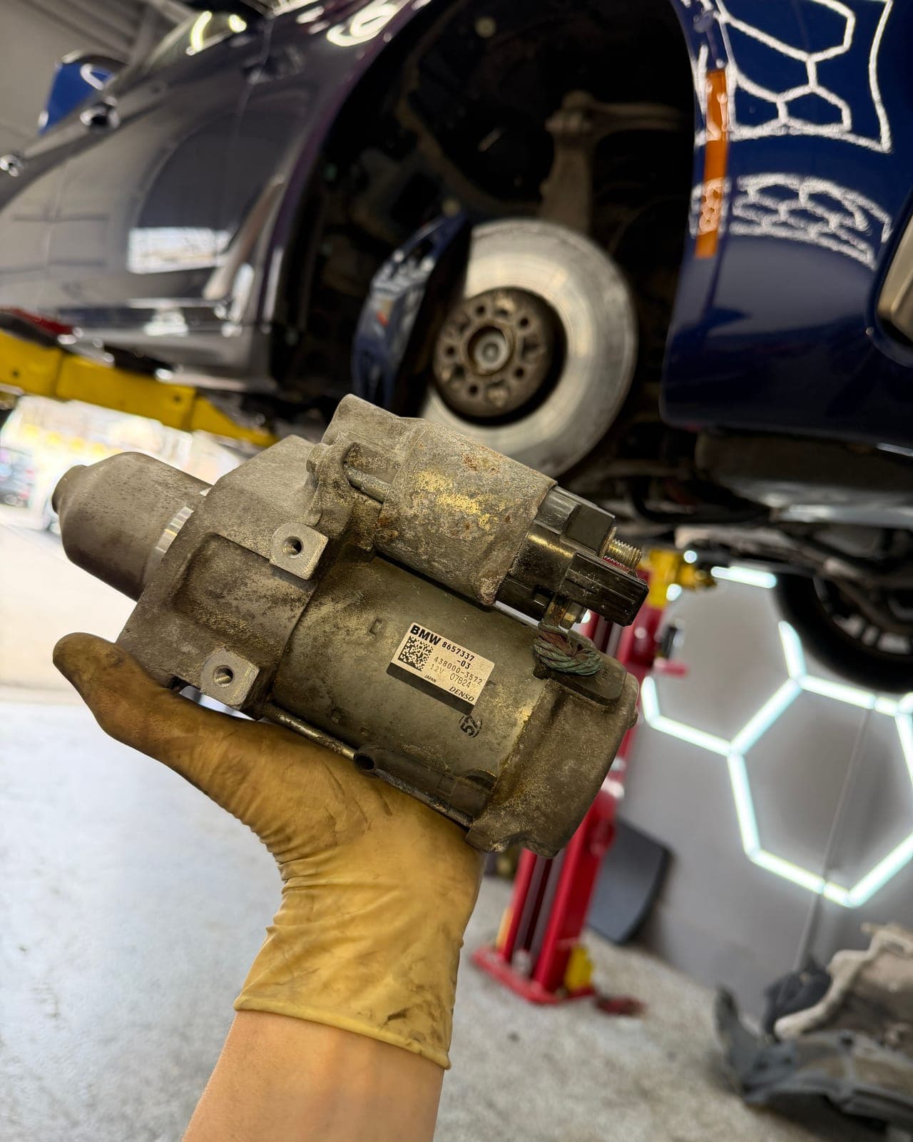 BMW engine bay during starter replacement with the intake assembly exposed.